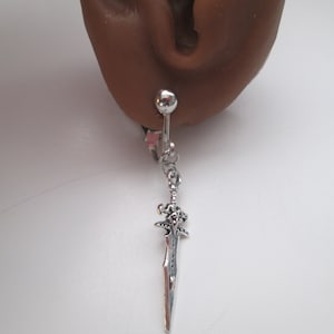 May include: Silver sword charm dangling from a silver barbell piercing. The barbell is inserted into a fake earlobe.