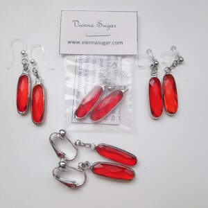 May include: Three pairs of red glass earrings with silver clip-on and hook backs. The earrings are rectangular in shape and have a faceted design. The packaging includes the text "Vienna Sugar" and "www.viennasugar.com".