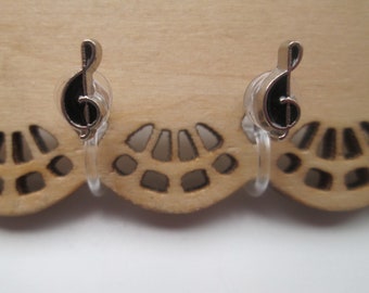 Peut inclure: Une paire de boucles d'oreilles clips argentées avec des breloques en forme de clé de sol noires.