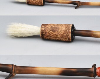 May include: A calligraphy brush with a bamboo handle and goat hair tip. The handle is a gradient of light brown to dark brown. The brush has a leather grip with an embossed design. A loop is attached to the end.