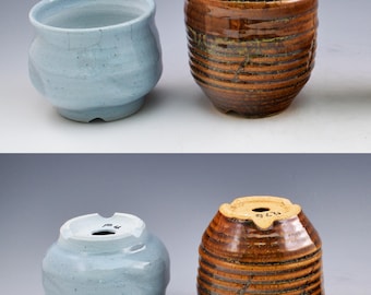 May include: Two ceramic pots, one light blue with a smooth glazed finish and one brown with a ribbed texture and dark glaze. Both pots feature a circular drainage hole on the bottom, with the blue pot marked P4 and the brown pot marked R76.
