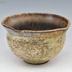 May include: A small, brown and yellow ceramic bowl with a textured surface. The bowl is approximately 2.7 inches tall and 4.7 inches wide.