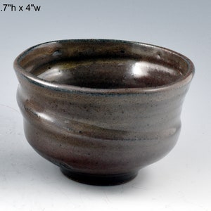 May include: A brown ceramic bowl with a wavy, textured surface. The bowl is 2.7 inches tall and 4 inches wide.