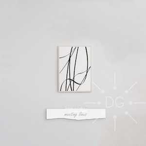 May include: An abstract art print in a white frame, showing black lines on a white background. The artwork is mounted on a light-coloured wall. Below the artwork is a white paper with the text "meeting lines".