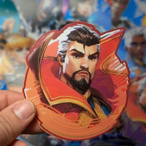 May include: A sticker featuring a cartoon illustration of a man with a beard wearing a red and gold robe. The man has a serious expression on his face. The sticker is on a white background.