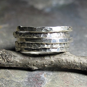 May include: A silver ring made of five stacked bands, each with a hammered texture.