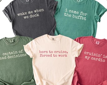 May include: A collection of six short-sleeved t-shirts in various colors, each with a unique, humorous phrase printed on the front. Colors include pepper, light green, moss, ivory, and crimson. The shirts are casual wear.
