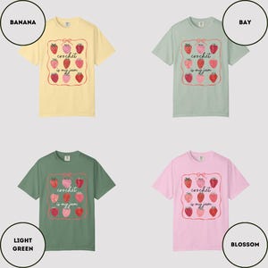 Puede incluir: Cuatro camisetas de manga corta en varios colores: amarillo pl&aacute;tano, verde claro, verde bah&iacute;a y rosa flor. Cada camiseta presenta un gr&aacute;fico de fresas con el texto "crochet is my jam" en un marco decorativo.