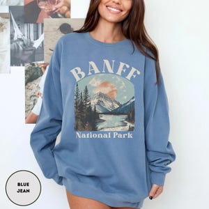 May include: A blue jean sweatshirt with a graphic print of a mountain landscape and the text "Banff National Park".