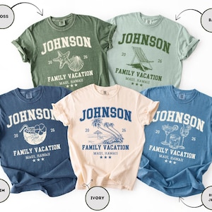 K&ouml;nnte beinhalten: F&uuml;nf T-Shirts in verschiedenen Farben: Moosgr&uuml;n, Bay-Gr&uuml;n, Denim-Blau, Elfenbein und Jeansblau. Jedes Shirt zeigt den Namen "JOHNSON" &uuml;ber "FAMILY VACATION MAUI, HAWAII" mit einer einzigartigen Grafik und der Zahl "26".