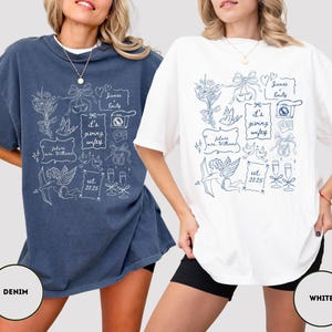 May include: Two oversized t-shirts, one denim blue and one white, featuring a whimsical doodle design in white and blue. The design includes text that says "it's giving wifey", "future mrs. Williams", and "est. 2025". The shirts are casual and comfortable.