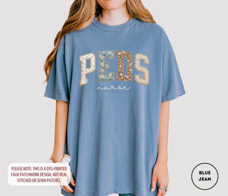 May include: A blue jean-colored t-shirt with the word "PEDS" in a faux patchwork design, with the word "nurse" below it. The letters have floral and patterned accents. The shirt is a comfortable, oversized fit.