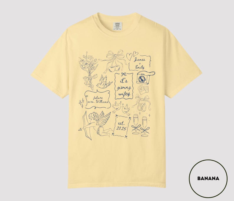 May include: A light yellow t-shirt with a navy blue graphic design. The design includes illustrations of flowers, bows, doves, a camera, champagne glasses, and text that reads "It's giving wifey", "future mrs. Williams", "James & Emily", and "est. 2025".