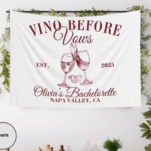 Peut inclure: Banni&egrave;re blanche avec le texte "Vino Before Vows" en lettres marrons. La banni&egrave;re comprend &eacute;galement le texte "Est. 2025", "Olivia's Bachelorette" et "Napa Valley, CA" en lettres marrons. Deux verres &agrave; vin avec du vin rouge sont repr&eacute;sent&eacute;s au centre de la banni&egrave;re, avec deux anneaux dor&eacute;s au-dessus des verres.