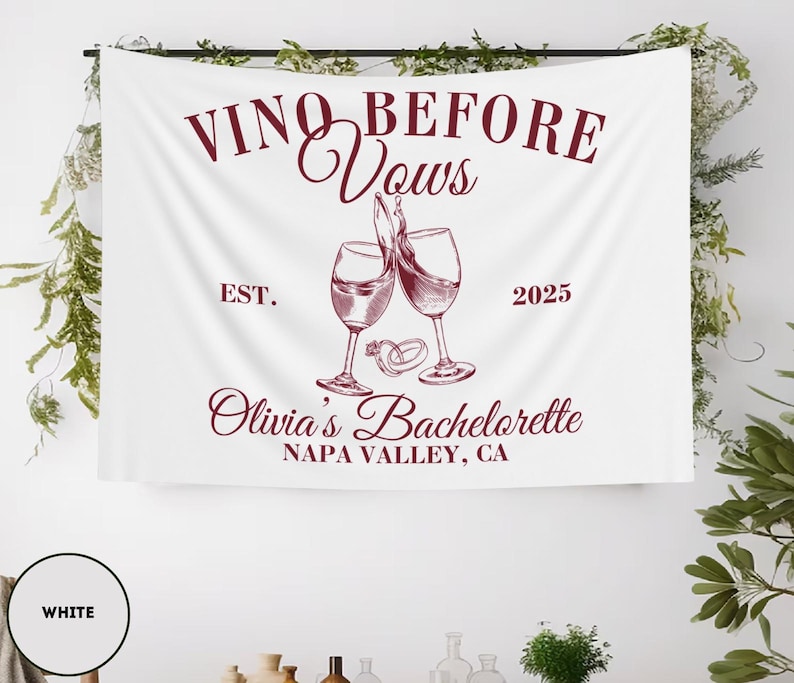 Peut inclure: Banni&egrave;re blanche avec le texte "Vino Before Vows" en lettres marrons. La banni&egrave;re comprend &eacute;galement le texte "Est. 2025", "Olivia's Bachelorette" et "Napa Valley, CA" en lettres marrons. Deux verres &agrave; vin avec du vin rouge sont repr&eacute;sent&eacute;s au centre de la banni&egrave;re, avec deux anneaux dor&eacute;s au-dessus des verres.
