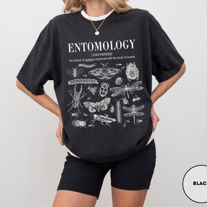 May include: Black t-shirt with a white print of the word "ENTOMOLOGY" and a definition of the word. The print also includes a variety of insects, including butterflies, beetles, and moths.