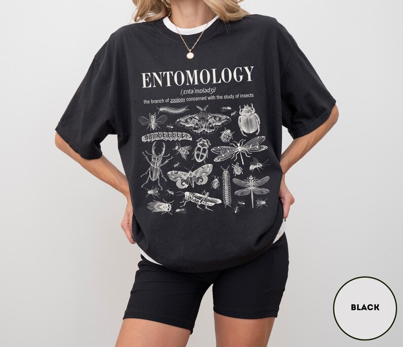 May include: Black t-shirt with a white print of the word "ENTOMOLOGY" and a definition of the word. The print also includes a variety of insects, including butterflies, beetles, and moths.