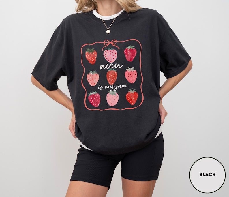 May include: Black t-shirt with a strawberry graphic and the text "NICU is my jam". The design features nine strawberries in various shades of red and pink, framed by a pink border and a bow.