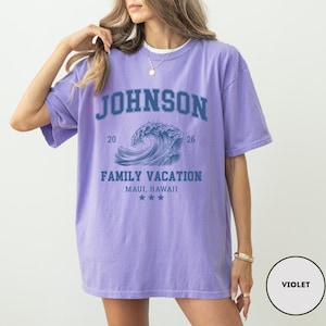 K&ouml;nnte beinhalten: Violettes T-Shirt mit kurzen &Auml;rmeln und Rundhalsausschnitt. Auf der Vorderseite steht in blauen Blockbuchstaben "JOHNSON" &uuml;ber einer blauen Wellengrafik. Darunter steht "FAMILY VACATION MAUI, HAWAII" und drei Sterne.