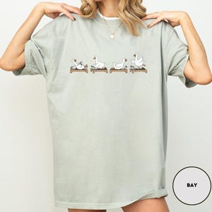 Puede incluir: Una taza de cer&aacute;mica blanca con un asa negra y el texto "But First, Coffee" en negrita negra. La taza se encuentra sobre un fondo borroso, sugiriendo un ambiente acogedor.