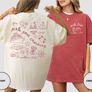 Puede incluir: Camisetas marfil y carmes&iacute; con gr&aacute;ficos tem&aacute;ticos de cruceros. La camiseta marfil presenta una impresi&oacute;n trasera con las palabras "girls gone cruising" e ilustraciones relacionadas con los cruceros. La camiseta carmes&iacute; tiene "girls trip" y un gr&aacute;fico de crucero.