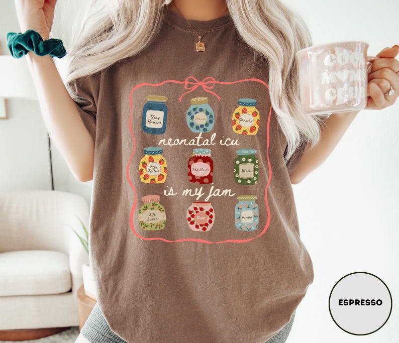 May include: Espresso-colored t-shirt featuring a colorful graphic of jam jars with the text "neonatal icu is my jam." The jars are filled with various fruits and labeled with text. The shirt is a casual, comfortable style.