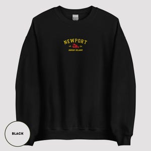 May include: Black sweatshirt featuring the word "NEWPORT" in yellow arched text above a red lobster graphic. Below the lobster are the numbers "16" and "39" and the words "Rhode Island" in yellow text. The sweatshirt is a Gildan brand.