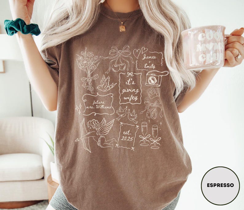 May include: Espresso-colored t-shirt with white line art illustrations, including flowers, doves, and the text "it's giving wifey." The shirt also features the text "future mrs. Williams" and "est. 2025."