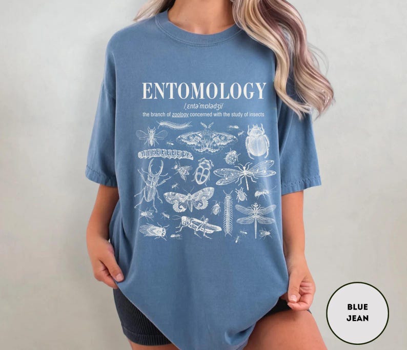 May include: A blue t-shirt with a white print of the word "ENTOMOLOGY" and a definition of the word. The print also includes a variety of insects, including butterflies, beetles, and dragonflies.