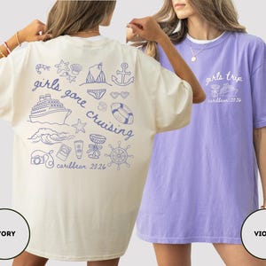 Puede incluir: Dos camisetas de gran tama&ntilde;o, una marfil y otra violeta. La camiseta marfil presenta un gr&aacute;fico azul con el texto "girls gone cruising caribbean 2026" e ilustraciones n&aacute;uticas. La camiseta violeta tiene "girls trip caribbean 2026" en blanco.