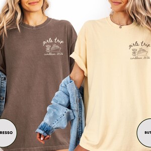 Puede incluir: Dos camisetas holgadas, una color espresso y otra color mantequilla, con el texto "girls trip caribbean 2026" y un gr&aacute;fico de un crucero y un c&oacute;ctel. Las camisetas tienen un corte relajado.