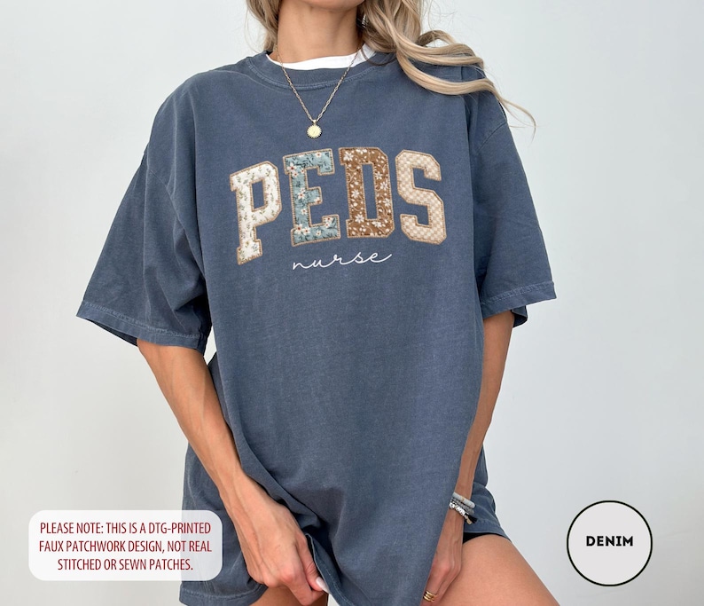May include: A denim blue t-shirt with the word "PEDS" in a faux patchwork design, with the word "nurse" underneath. The shirt has short sleeves and a relaxed fit. The text "PLEASE NOTE: THIS IS A DTG-PRINTED FAUX PATCHWORK DESIGN, NOT REAL STITCHED OR SEWN PATCHES." is at the bottom.