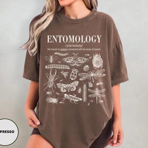 May include: A brown t-shirt with a white print of insects and the text "ENTOMOLOGY /enta moladzil/ the branch of zoology concerned with the study of insects"