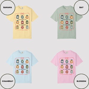 May include: Four short-sleeved t-shirts in banana yellow, bay green, chambray blue, and blossom pink. Each shirt features a graphic of jam jars with the text "neonatal icu is my jam" in a decorative frame.