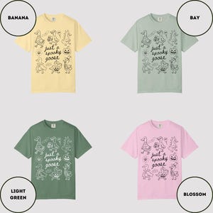 May include: Four t-shirts in various colors: banana, bay, light green, and blossom. Each shirt features a black graphic of cartoon geese and pumpkins with the text "just a spooky goose".