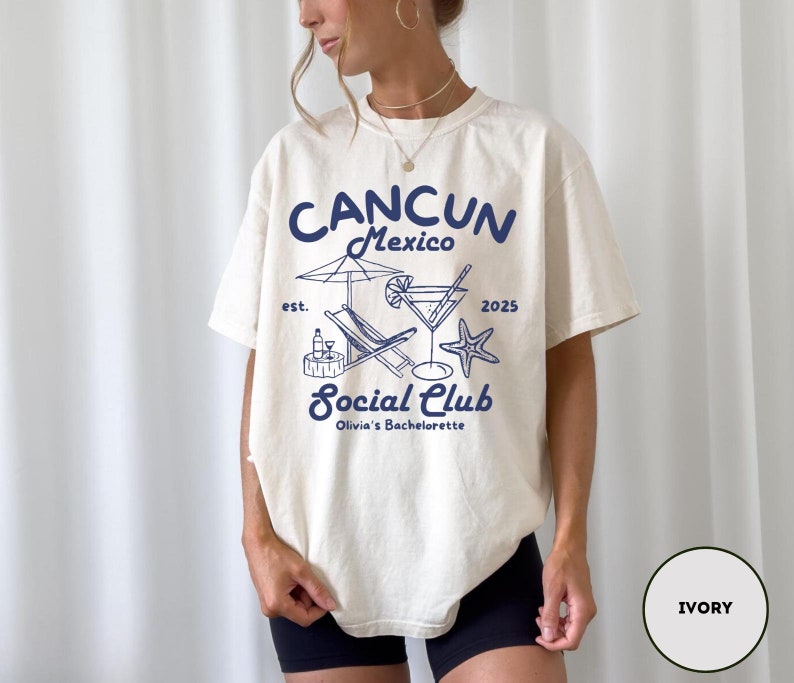 May include: Ivory t-shirt with a blue graphic design that says "Cancun Mexico est. 2025 Social Club Olivia's Bachelorette" with a cocktail glass, beach chair, and starfish.