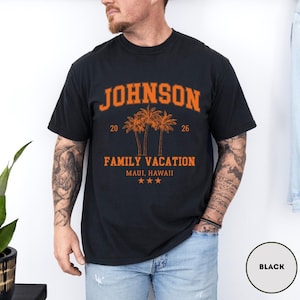 K&ouml;nnte beinhalten: Schwarzes T-Shirt mit orangefarbenem Text "JOHNSON" &uuml;ber einer Grafik von drei Palmen und den Worten "FAMILY VACATION MAUI, HAWAII". Das Shirt hat auch die Zahlen "20" und "26" und drei Sterne.