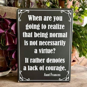 May include: Black wooden sign with white text that reads "When are you going to realize that being normal is not necessarily a virtue? It rather denotes a lack of courage. Aunt Frances"