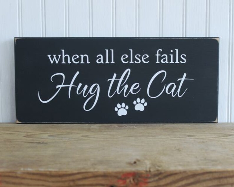 Black wood sign with white lettering saying When all else fails Hug the Cat.  Two white cat paw prints.  Sign measures 6x14 inches.