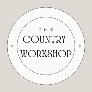 May include: A white circle with a black border and two smaller circles inside. The text "THE COUNTRY WORKSHOP" is written in black inside the circles.