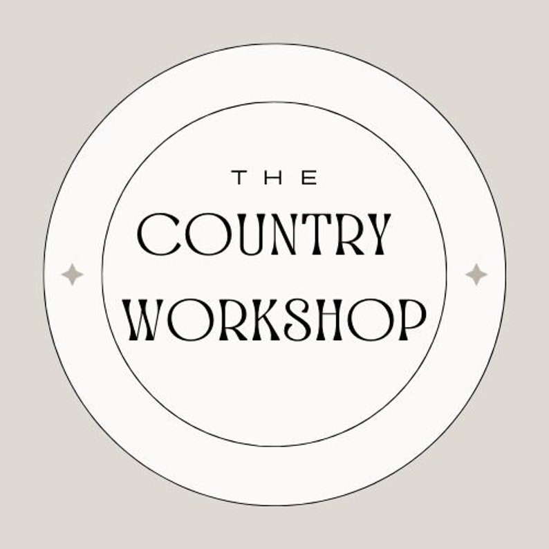 May include: A white circle with a black border and two smaller circles inside. The text "THE COUNTRY WORKSHOP" is written in black inside the circles.