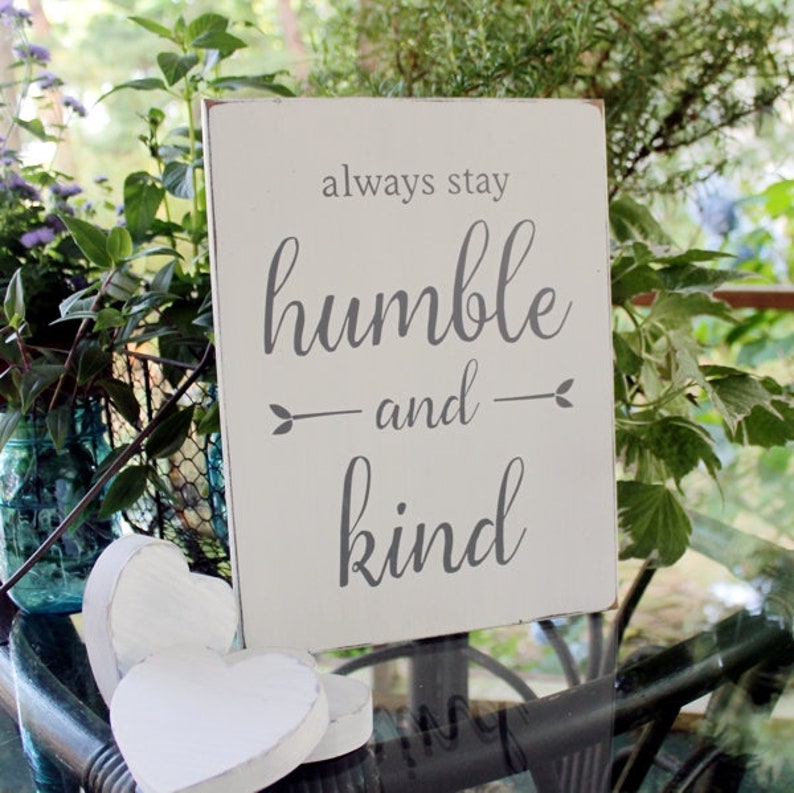 9x12 inch white wood sign, slightlt worn finish with gray lettering saying always stay humble and kind.