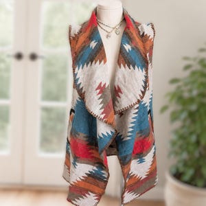 May include: A sleeveless waistcoat featuring a wide draped collar and a geometric pattern in shades of blue, red, orange, brown, and cream. The garment has a visible whipstitch edge detail along the collar and hem, displayed on a mannequin.
