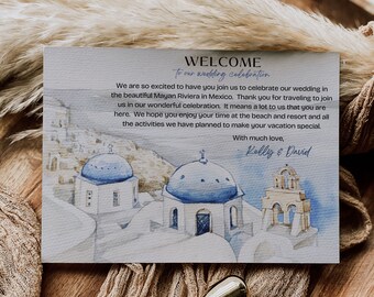 May include: A welcome card with a watercolor illustration of white buildings with blue domes, set against a blue sky. The card reads "Welcome to our wedding celebration." and includes the text "We are so excited to have you join us to celebrate our wedding in the beautiful Mayan Riviera in Mexico. Thank you for traveling to join us in our wonderful celebration. It means a lot to us that you are here. We hope you enjoy your time at the beach and resort and all the activities we have planned to make your vacation special. With much love, Kelly & David."