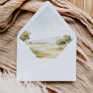 May include: A white envelope featuring a watercolour illustration of a landscape scene. The scene depicts a grassy field, trees, and a mountain range in the distance. The sky is a light blue colour.