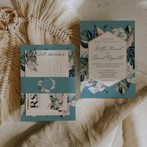 May include: A tropical-themed wedding invitation with a blue background and gold accents. The invitation features a floral design with palm leaves and orchids. The text reads "Together with their families Kelly Steward and David Reynolds invite you to celebrate their wedding July 10, 2024 at 3:00PM to be held at the Royal Hideaway Playacar Playa del Carmen Riviera Maya, Mexico Reception to follow."