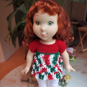 May include: A red, white, and green crocheted dress with short sleeves on a doll with red hair.