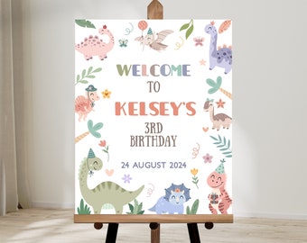 May include: Welcome to Kelsey's 3rd Birthday sign with a dinosaur theme. The sign features a white background with colorful dinosaurs, flowers, and leaves. The text "Welcome to Kelsey's 3rd Birthday" is written in a colorful font. The date "24 August 2024" is also included on the sign.