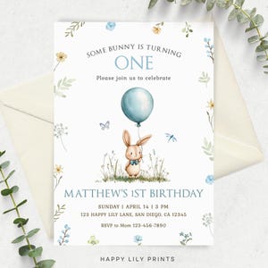 May include: A blue and white birthday invitation with a cute bunny rabbit holding a blue balloon. The invitation says "Some bunny is turning one" and "Matthew's 1st Birthday".