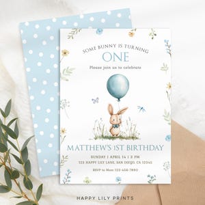 May include: A blue and white polka dot envelope with a white card inside. The card has a watercolor illustration of a bunny holding a blue balloon. The text on the card reads "Some bunny is turning one. Please join us to celebrate. Matthew's 1st Birthday. Sunday | April 14 | 3 PM. 123 Happy Lily Lane, San Diego, CA 12345. RSVP to Mom 123-456-7890. Happy Lily Prints."